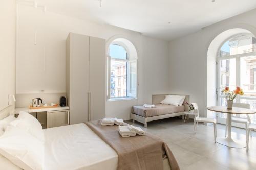 Dormitorio blanco con cama y mesa en Lux Caracciolo en Nápoles