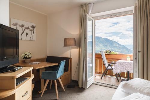 a hotel room with a desk and a balcony at Hotel & Residence Rebhof in Tirolo