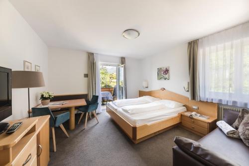 a hotel room with a bed and a desk at Hotel & Residence Rebhof in Tirolo