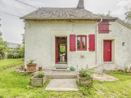 una pequeña casa blanca con persianas rojas en Country house near Canal du Nivernais, en Devay