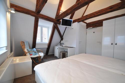 a bedroom with a white bed and a chair at Soleiado Hotel in Bietigheim-Bissingen