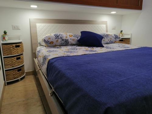 Una cama con sábanas azules y almohadas en un dormitorio en Casetta Rosso Tulipano, en Santa Teresa di Riva