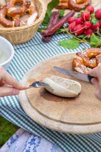 a person holding a fork and knife on a cutting board at Hotel Dirsch Wellness & Spa Resort in Emsing