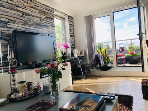 ein Wohnzimmer mit einem TV und einem Tisch mit Blumen in der Unterkunft Beautiful apartment in SW London in Sutton
