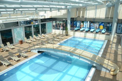 a large swimming pool in a building with chairs at Mercure Istanbul West Hotel & Convention Center in Istanbul