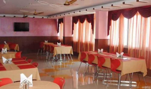 a dining room with tables and chairs and red curtains at Hotel Shail Shikhar in Joshīmath