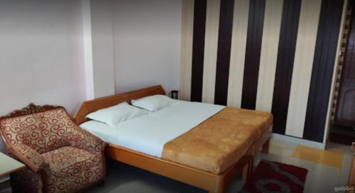 a small bedroom with a bed and a chair at Hotel Shail Shikhar in Joshīmath