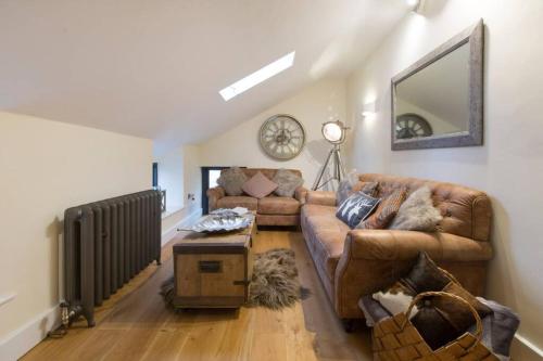 a living room with a couch and a mirror at New Loos Cottage, Old School Court in Stow on the Wold