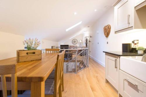 a kitchen and dining room with a wooden table at New Loos Cottage, Old School Court in Stow on the Wold