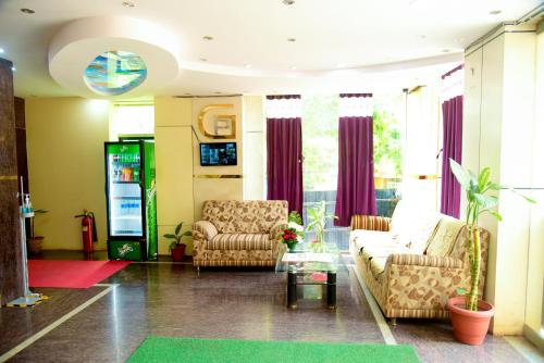 a living room with two chairs and a couch at Grand Plaza in Dhārwād