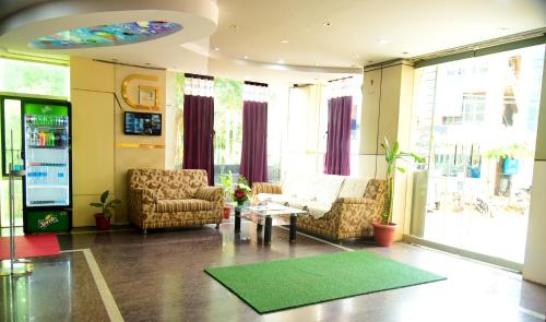 a living room with a couch and chairs and a table at Grand Plaza in Dhārwād