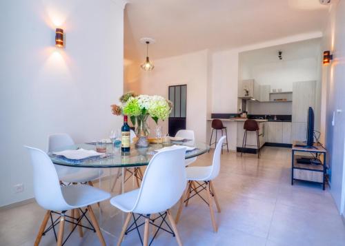 une salle à manger avec une table en verre et des chaises blanches dans l'établissement Grand appartement 4 pièces centre de Cannes, à Cannes