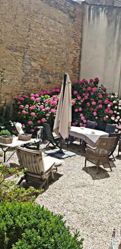 un patio con mesa, sombrilla y flores en Maponi, en Dijon