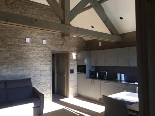 une cuisine avec des placards blancs et un mur en briques dans l'établissement GITE AVEC VUE MAGNIFIQUE, à Saint-Étienne-lès-Remiremont