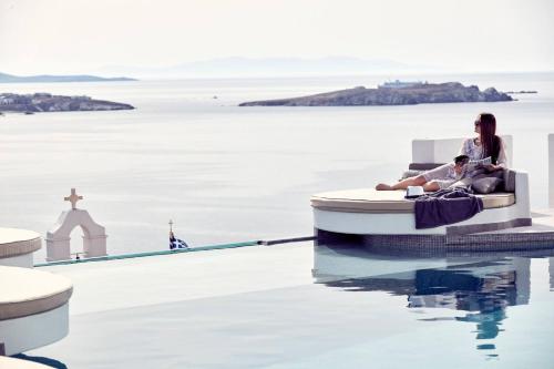 a man and a woman sitting on a boat in the water at Absolute Mykonos Suites & More in Mýkonos City