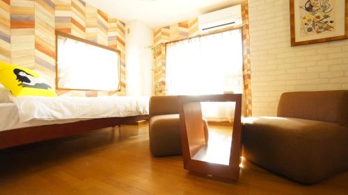 a bedroom with a bed and a couch and a chair at Tomato Takayama Station in Takayama