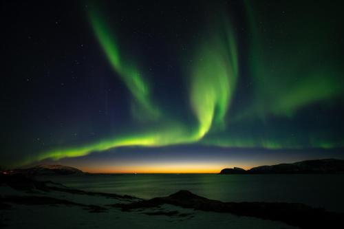 an aurora in the sky over a body of water at The Crush in Ersfjordbotn