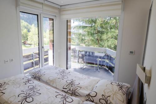 ein Schlafzimmer mit einem Bett und einem großen Fenster in der Unterkunft Haus Cristal in Leukerbad