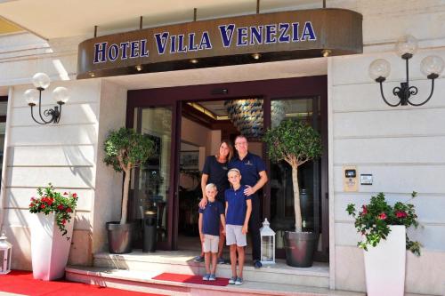 uma família posando em frente a uma villa de hotel veneta em Hotel Villa Venezia em Grado