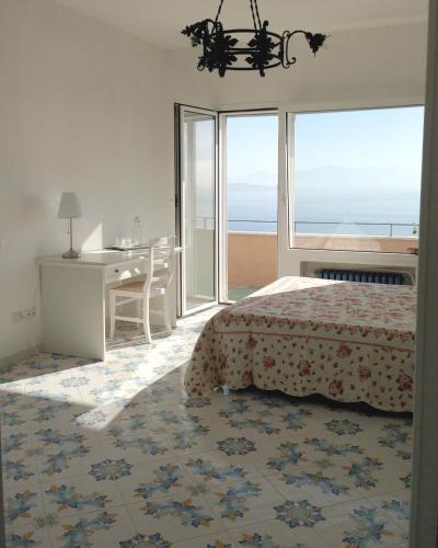 a bedroom with a bed and a desk with a view of the ocean at B&B Dipintodiblu' in Naples
