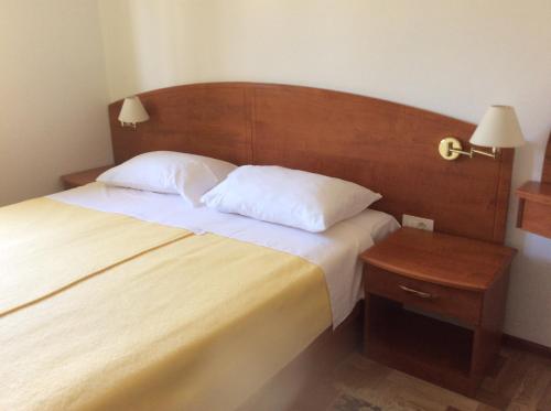 - une chambre avec un grand lit et une tête de lit en bois dans l'établissement Villa Jadranka, à Rab