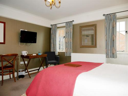 a bedroom with a bed and a desk and a television at The Angel in Wootton Bassett in Royal Wootton Bassett