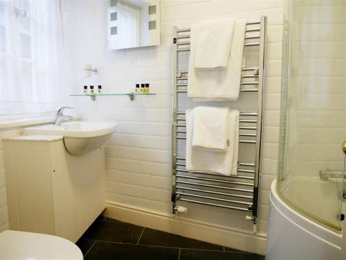 a bathroom with a sink and a toilet and towels at The Angel in Wootton Bassett in Royal Wootton Bassett
