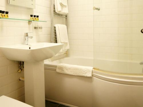 a white bathroom with a sink and a tub and a sink at The Angel in Wootton Bassett in Royal Wootton Bassett