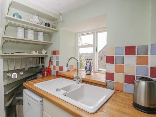 a kitchen with a white sink and a window at Athelstan Cottage in Stroud