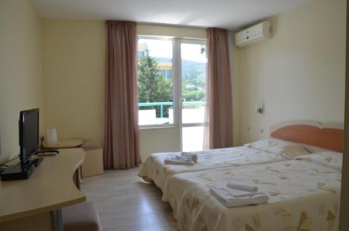 a hotel room with a bed and a window at Sania in Obzor