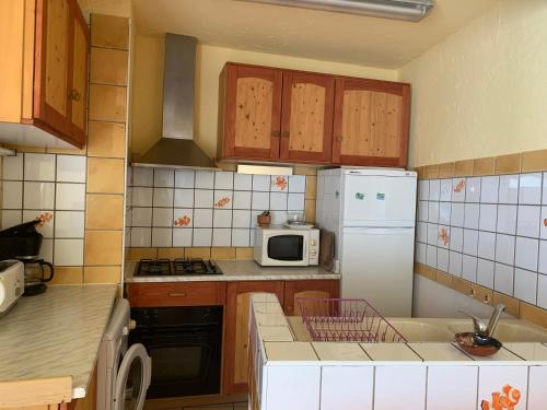 a kitchen with wooden cabinets and a white refrigerator at SAINT ANTOINE in Marcoux