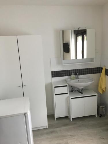 uma casa de banho branca com um lavatório e um espelho em Gemütliches Ferienzimmer Hürth em Hürth