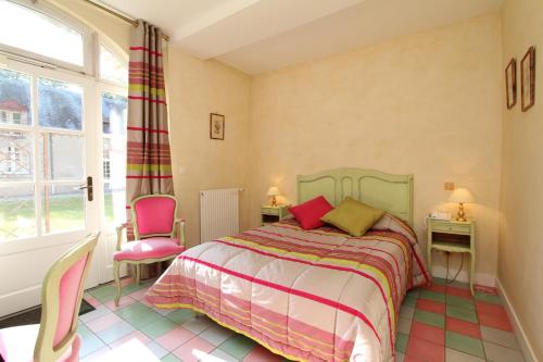 a bedroom with a bed and two pink chairs at Hostellerie Du Château Les Muids in La Ferté-Saint-Aubin