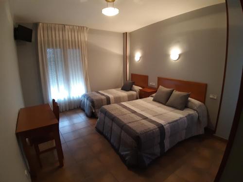 a hotel room with two beds and a table at Hotel Los Leones, el más cercano a Warner in San Martín de la Vega