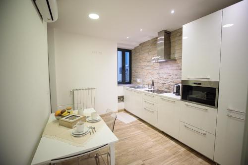 una cucina con armadi bianchi e piano di lavoro bianco di la Maison de Trieste Suite garage a Trieste