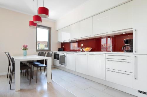 a kitchen with white cabinets and a table with chairs at Elite Apartments Waterlane Swimming Pool&aSpa in Gdańsk