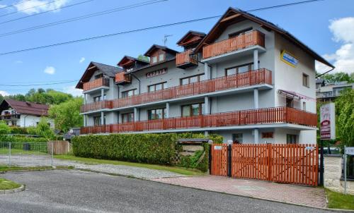 a large white building with a red fence at Willa Cyprys - pokoje i apartamenty z aneksami - Centrum in Wisła