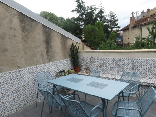 une terrasse avec une table et des chaises sur un mur dans l'établissement le 12, à Villefranche-de-Rouergue