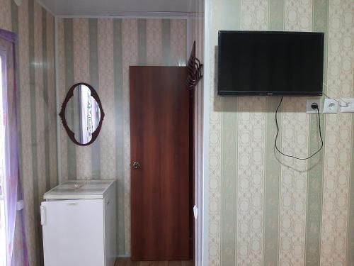 een flatscreen-tv aan een muur naast een badkamer bij Mini Hotel Уютный дворик in Odessa