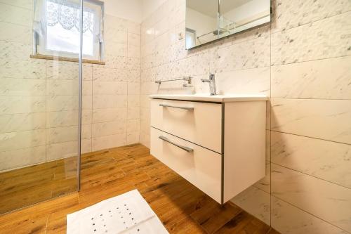 a white bathroom with a sink and a shower at Apartments Jurina 2 in Krk