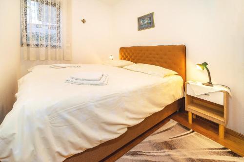 1 dormitorio con 1 cama con sábanas blancas y lámpara en Apartments Jurina 2, en Krk