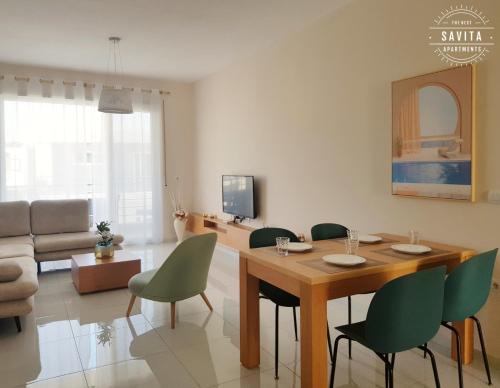 - un salon avec une table en bois et des chaises vertes dans l'établissement Gjiri i Lalzit - Savita Apartments - Kompleksi Turistik Lura 3, à Mullini i Danit