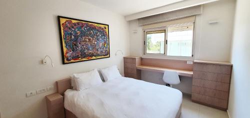 een slaapkamer met een wit bed en een raam bij BnBIsrael apartments - Ramat Yam Marine in Herzelia 