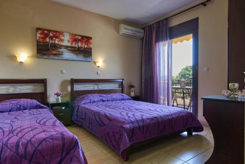 a hotel room with two beds and a balcony at Fotini House in Sarti