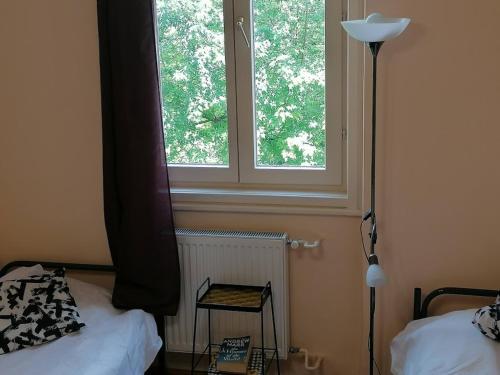 Dormitorio con ventana, cama y lámpara en Bauhaus Astoria Hostel en Budapest