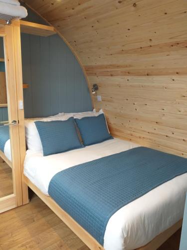 a bed in a room with a wooden wall at North Star Glamping in Lybster