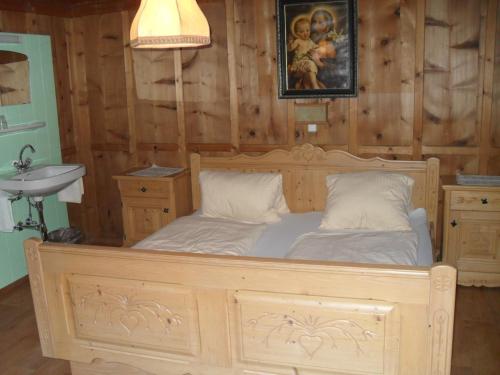 Cama de madera en habitación con lavabo en Haus Schellenschmied, en Pettneu am Arlberg