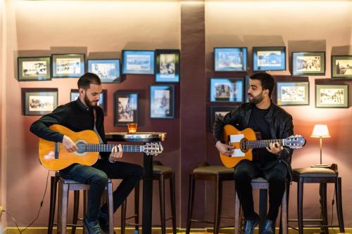 two men sitting on bar stools playing guitars at Palais Faraj Suites & Spa in Fès