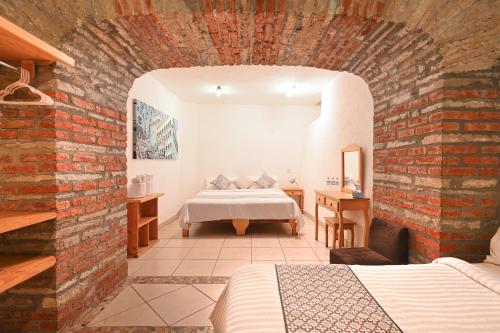 a bedroom with a bed and a brick wall at Hotel Meson Cuevano in Guanajuato