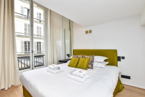 a bedroom with a bed and a large window at CMG Résidence Palais de l'Elysée/ Saint-Honoré in Paris